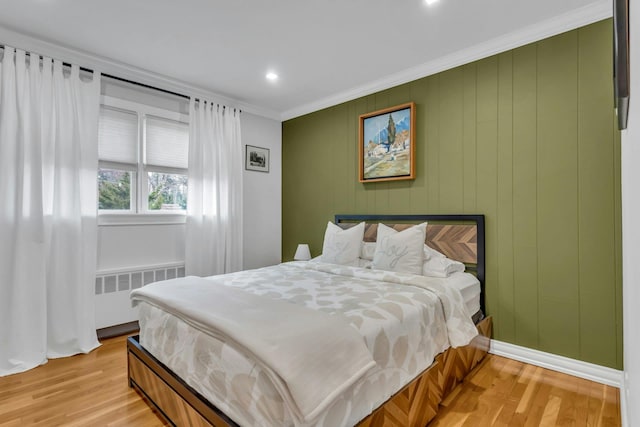 bedroom with crown molding, radiator heating unit, and light wood-type flooring