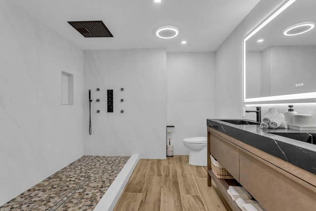 bathroom featuring a shower, hardwood / wood-style floors, vanity, and toilet