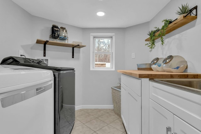 laundry area featuring cabinets, light tile patterned floors, and washing machine and clothes dryer