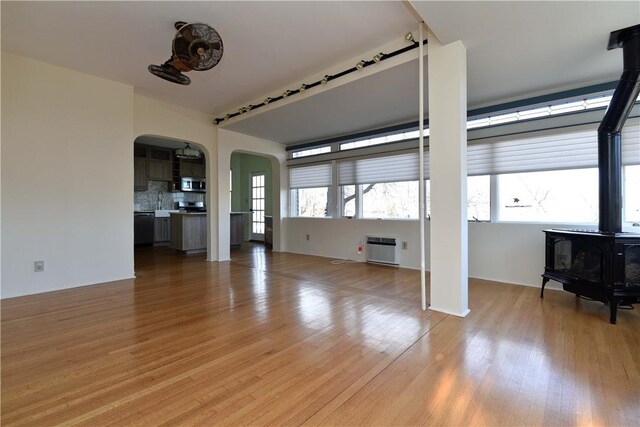 unfurnished living room with light wood-type flooring, a wood stove, and sink