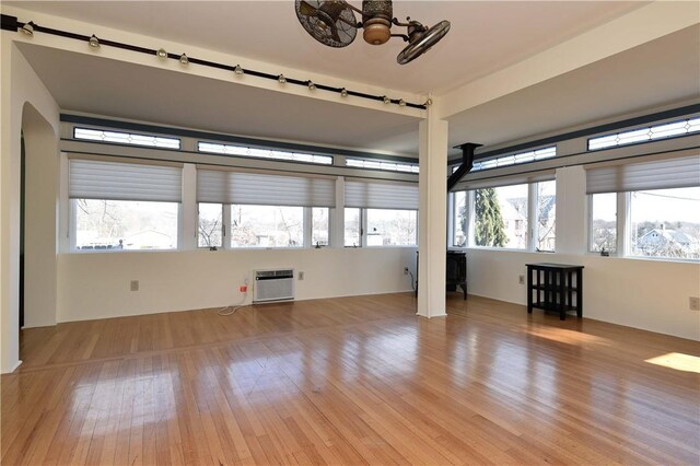 empty room featuring a healthy amount of sunlight, light hardwood / wood-style floors, and a wall mounted air conditioner