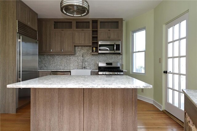 kitchen featuring a center island, backsplash, sink, appliances with stainless steel finishes, and light hardwood / wood-style floors