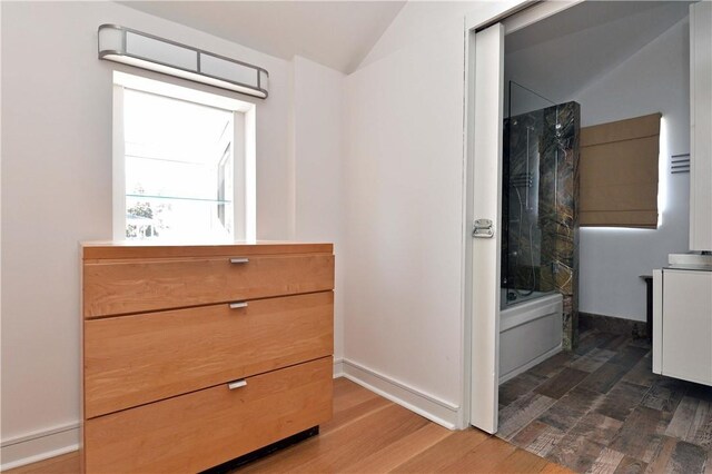 bathroom with vanity, shower / bath combination, lofted ceiling, and hardwood / wood-style flooring