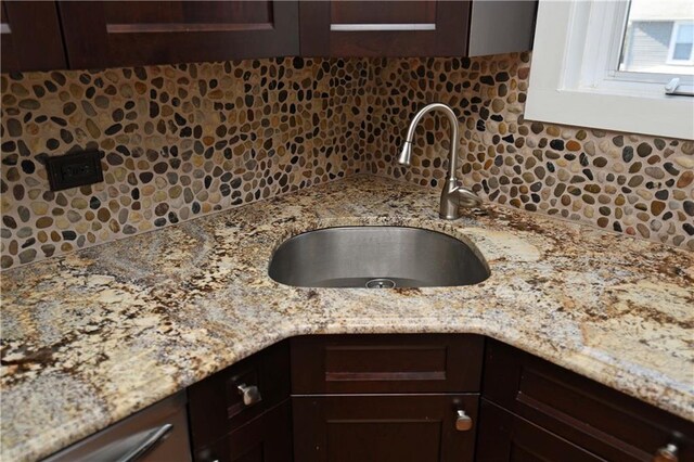 details with light stone countertops, dark brown cabinetry, and sink