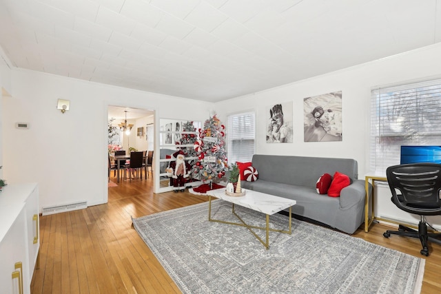 living room featuring baseboard heating, light wood-type flooring, and a healthy amount of sunlight