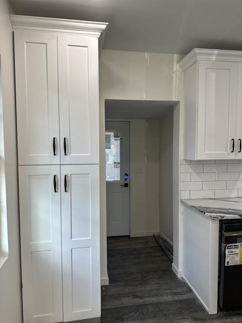 kitchen featuring light stone counters, dark wood-style flooring, white cabinetry, and decorative backsplash