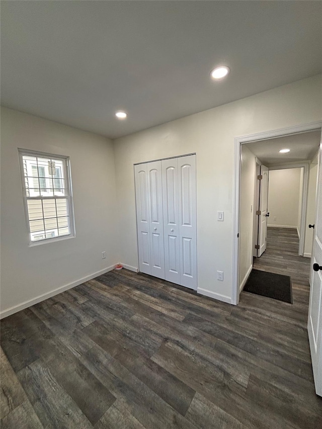 unfurnished bedroom with baseboards, dark wood finished floors, a closet, and recessed lighting