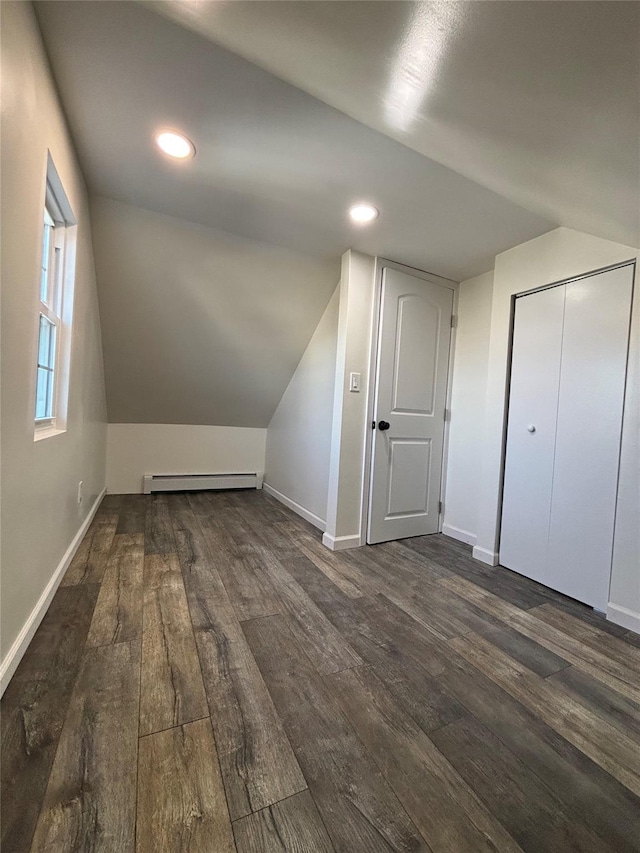 additional living space featuring a baseboard heating unit, baseboards, dark wood finished floors, and lofted ceiling