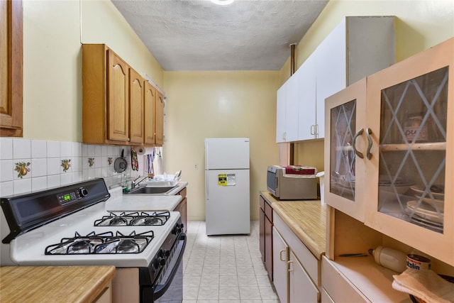 kitchen with black gas range, white refrigerator, sink, decorative backsplash, and a textured ceiling