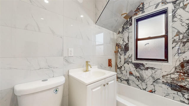 bathroom featuring vanity, a tub to relax in, toilet, and tile walls