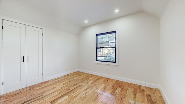 unfurnished bedroom featuring a closet, light hardwood / wood-style flooring, and lofted ceiling