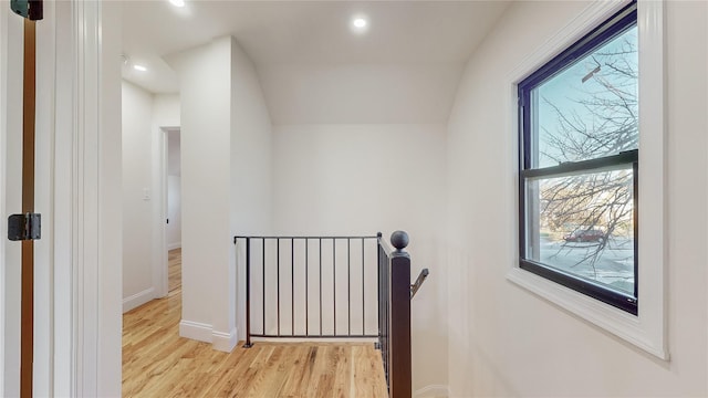 corridor featuring plenty of natural light, lofted ceiling, and light wood-type flooring