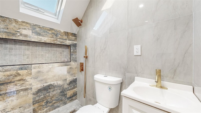 bathroom with vanity, a skylight, toilet, and tile walls