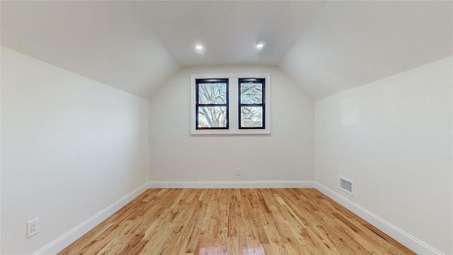 additional living space featuring light wood-type flooring and vaulted ceiling