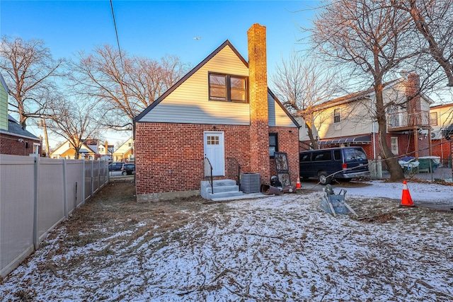 snow covered rear of property featuring cooling unit