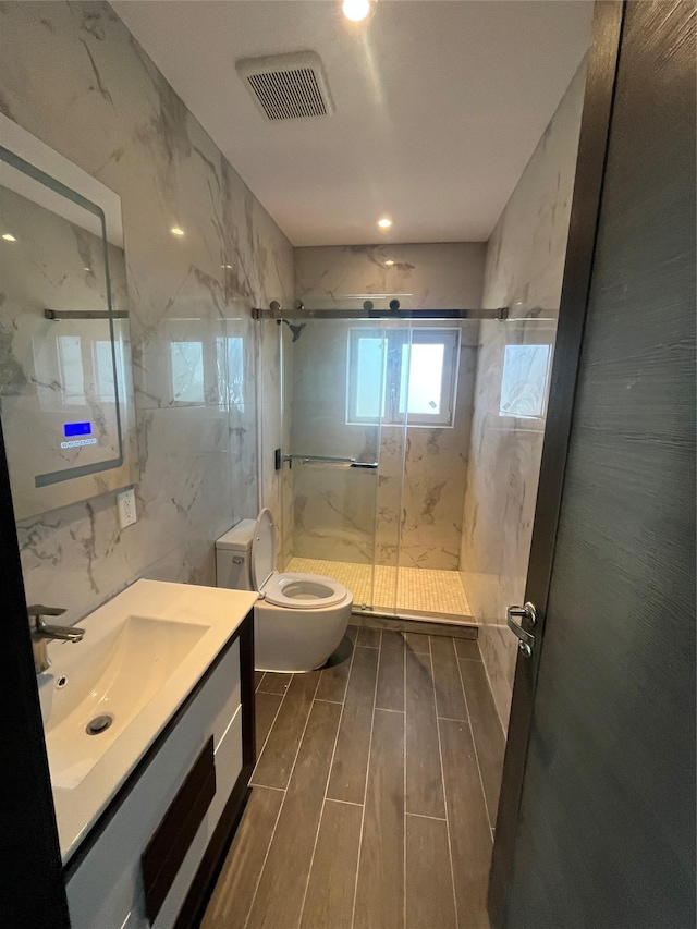 bathroom with vanity, toilet, tile walls, and a shower with shower door