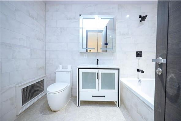 full bathroom featuring tile walls, visible vents, tiled tub, toilet, and tiled shower