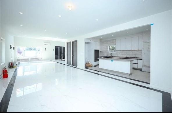 kitchen featuring marble finish floor, modern cabinets, tasteful backsplash, white cabinetry, and a large island