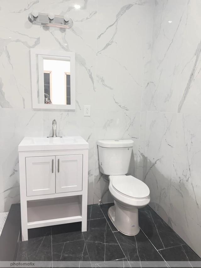 bathroom featuring vanity, toilet, and tile walls