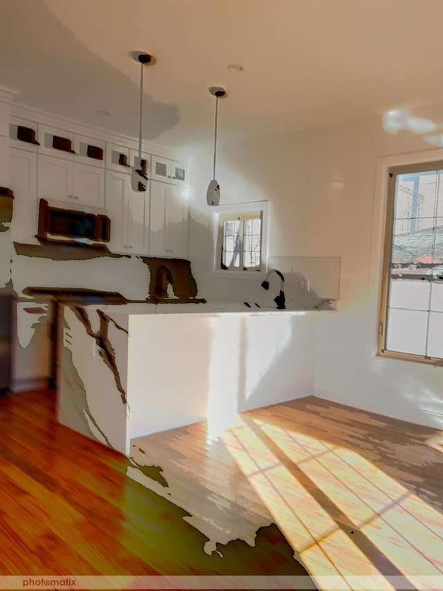 kitchen with white cabinets, pendant lighting, light hardwood / wood-style floors, and plenty of natural light