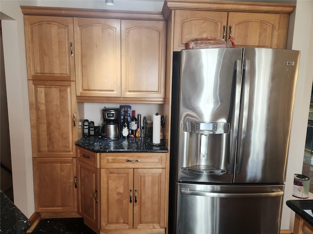 kitchen with stainless steel fridge and dark stone countertops