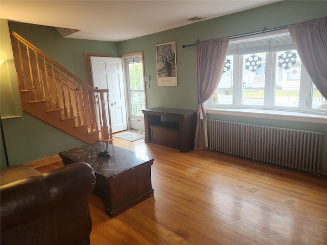 living room with a wealth of natural light, light hardwood / wood-style flooring, and radiator