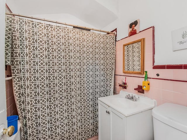 bathroom with vanity, toilet, and tile walls