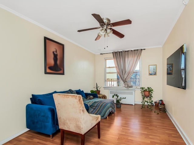 living area with hardwood / wood-style floors, radiator, ornamental molding, and ceiling fan