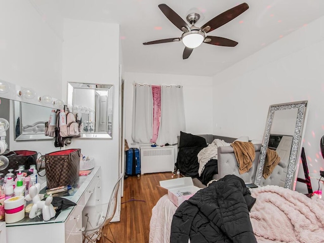 bedroom featuring ceiling fan, radiator heating unit, and dark wood-type flooring