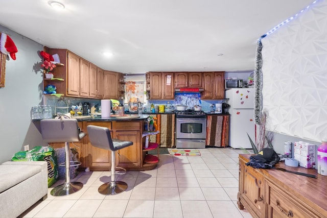 kitchen with backsplash, light tile patterned floors, and appliances with stainless steel finishes