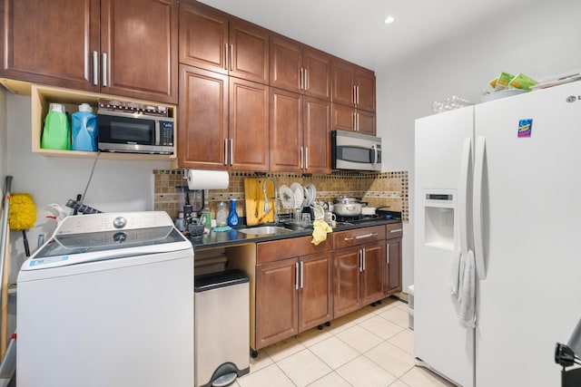 kitchen featuring tasteful backsplash, sink, light tile patterned floors, washer / dryer, and white fridge with ice dispenser