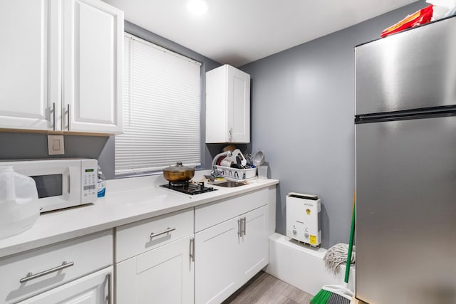 kitchen featuring stainless steel fridge, white cabinetry, sink, and light hardwood / wood-style flooring