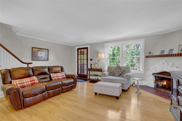 living room featuring crown molding, light hardwood / wood-style flooring, and a high end fireplace