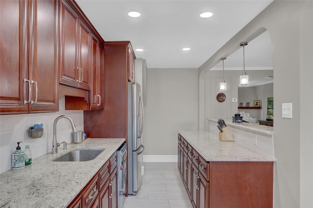 kitchen featuring hanging light fixtures, sink, ornamental molding, appliances with stainless steel finishes, and light stone counters