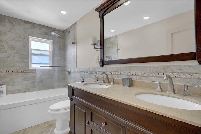 full bathroom featuring tile patterned floors, vanity, tiled shower / bath combo, tile walls, and toilet