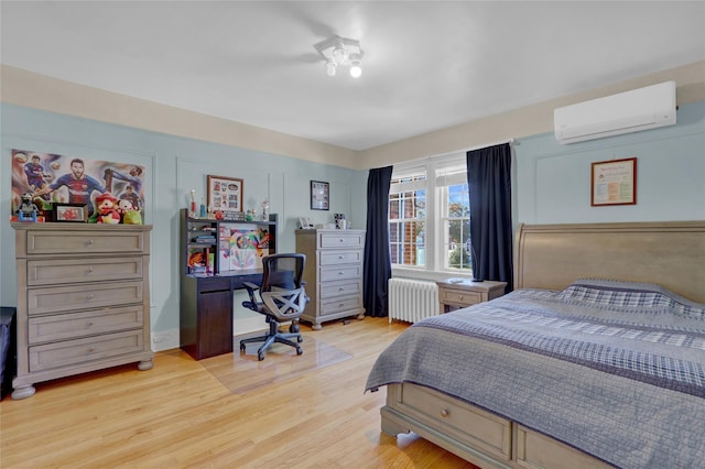 bedroom featuring light wood-type flooring, an AC wall unit, and radiator