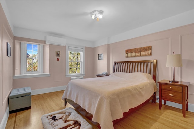 bedroom featuring light hardwood / wood-style flooring and a wall unit AC