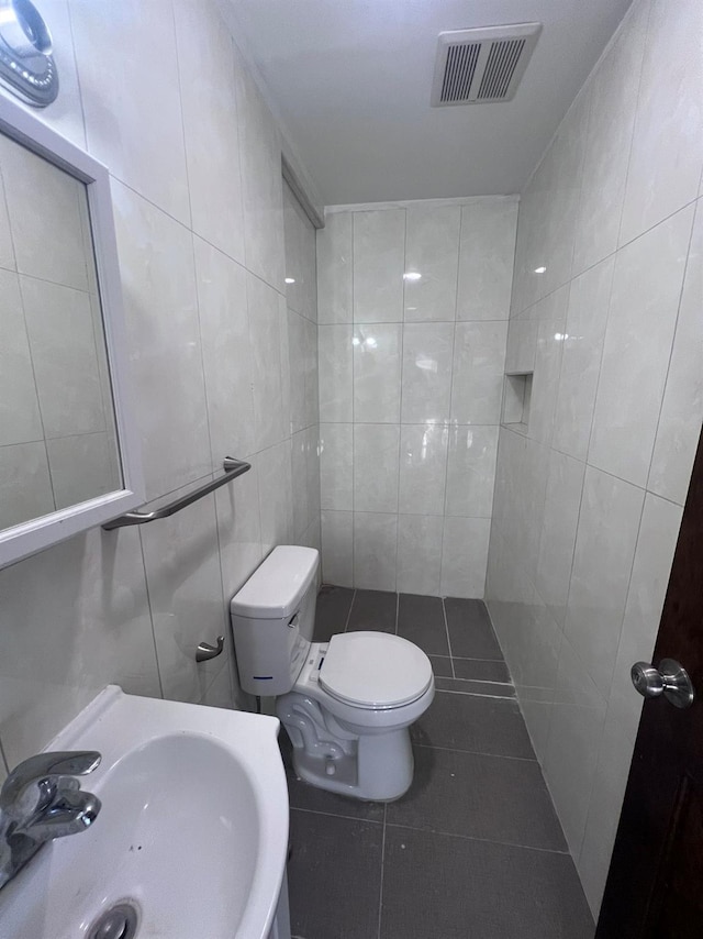 bathroom featuring tile patterned floors, sink, tile walls, and toilet