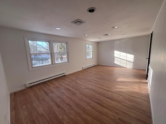 spare room featuring wood-type flooring and a baseboard heating unit