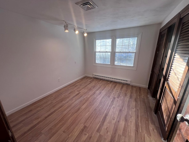 unfurnished room featuring wood-type flooring and baseboard heating