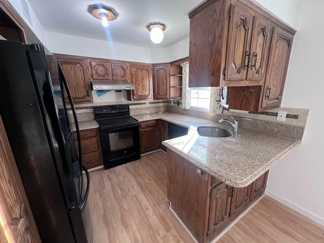 kitchen with sink, range hood, kitchen peninsula, black appliances, and light wood-type flooring