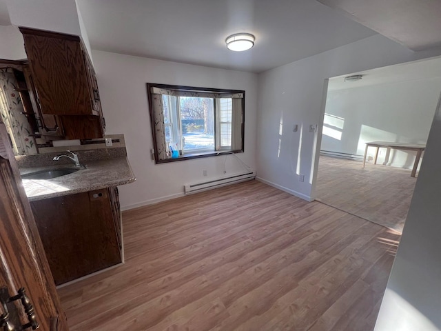 unfurnished dining area featuring sink, light hardwood / wood-style floors, and a baseboard heating unit