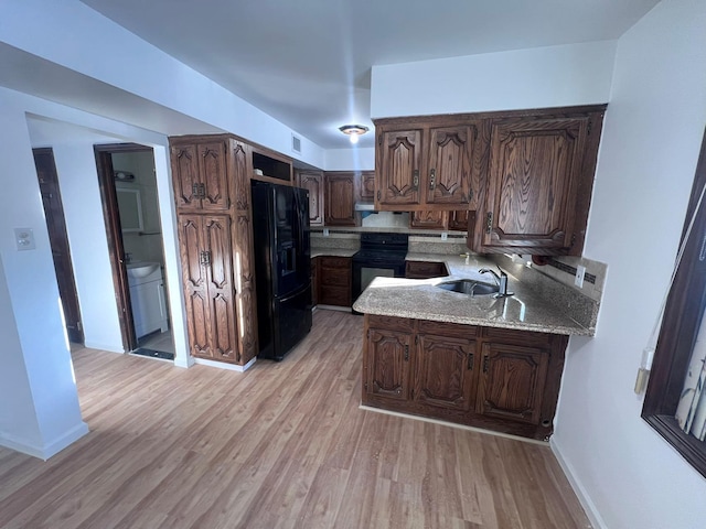 kitchen featuring light stone countertops, dark brown cabinetry, sink, black appliances, and light hardwood / wood-style flooring