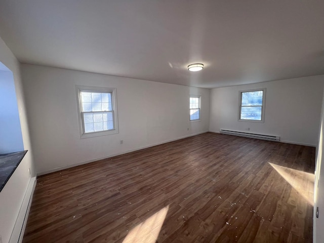 empty room featuring a healthy amount of sunlight, dark hardwood / wood-style flooring, and a baseboard radiator