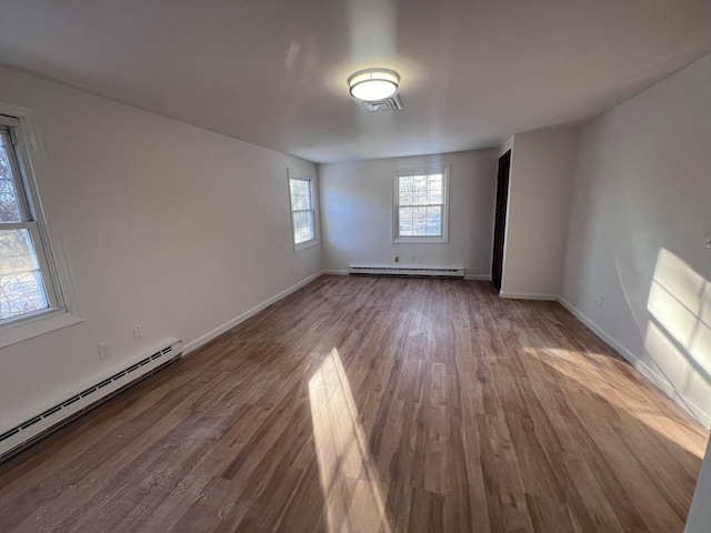 unfurnished room featuring baseboard heating and hardwood / wood-style flooring