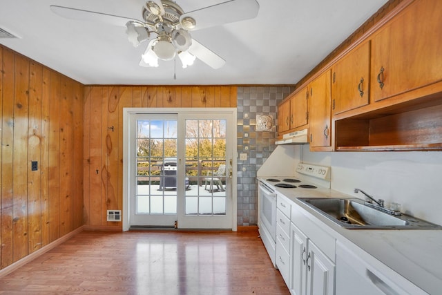 kitchen featuring white cabinets, white appliances, wood walls, and sink