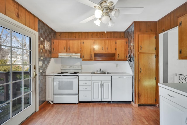 kitchen with white appliances, ceiling fan, wood walls, and sink