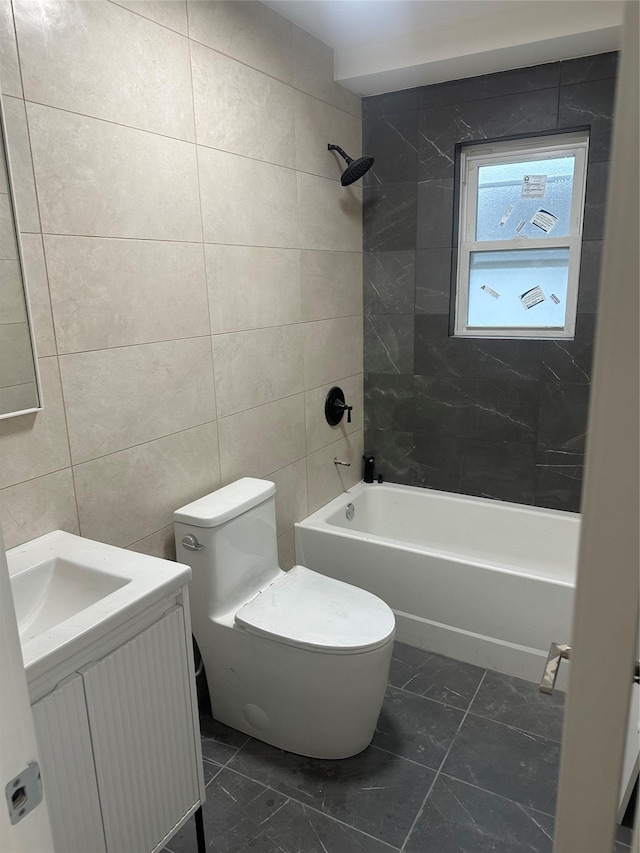 full bathroom featuring tile walls, vanity, tiled shower / bath combo, and toilet