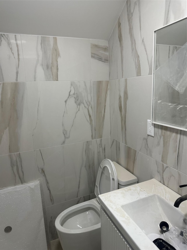 bathroom with vanity, tile walls, and toilet