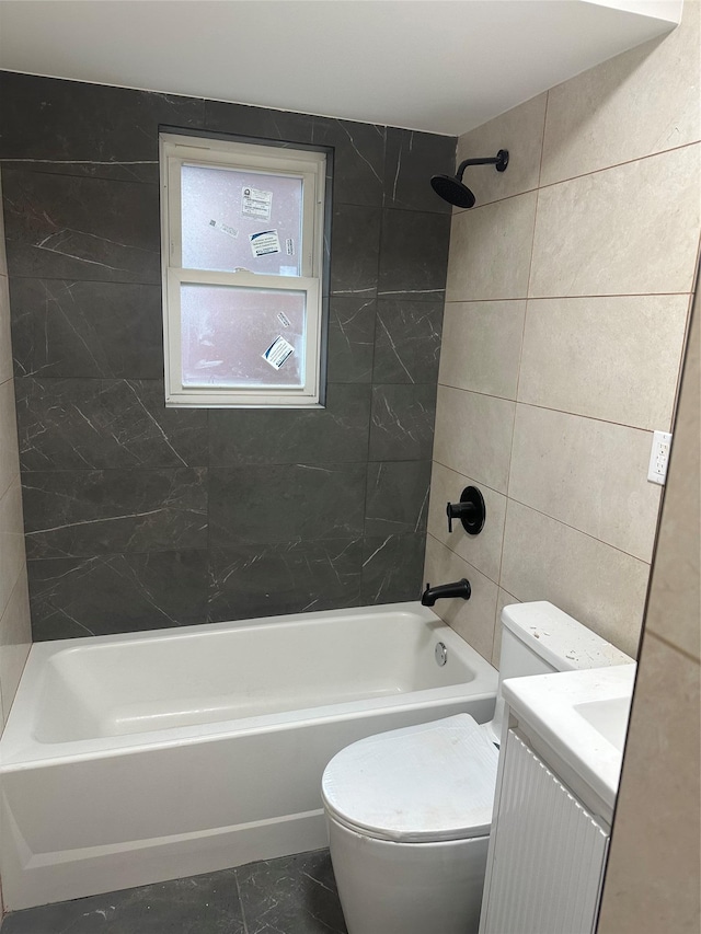 full bathroom with vanity, tiled shower / bath combo, toilet, and tile walls